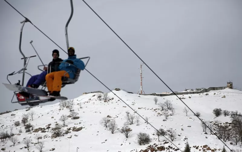Skiers sit on a chairlift as an Israeli army base is seen in the background at the Israeli Mount Hermon ski resort, in the Israeli-occupied Golan Heights, on January 21, 2016.
For Israelis, the Hermon range, straddling Lebanon and the Syrian and Israeli-held sectors of the Golan, is a highly strategic area under close surveillance. / AFP / THOMAS COEX / TO GO WITH AFP STORY BY DAPHNE ROUSSEAU