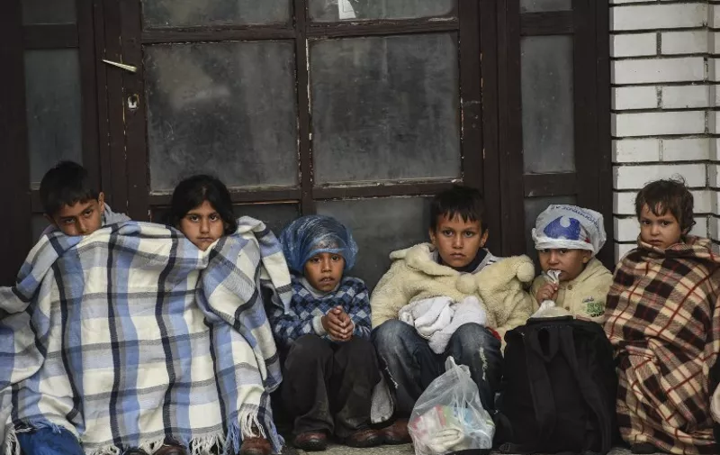 Children sit under covers as they wait with migrants and refugees near the registration camp in the town of Presevo after their arrival in Serbia, on September 10, 2015. The EU unveiled plans to take 160,000 refugees from overstretched border states, as the United States said it would accept more Syrians to ease the pressure from the worst migration crisis since World War II. AFP PHOTO / ARMEND NIMANI