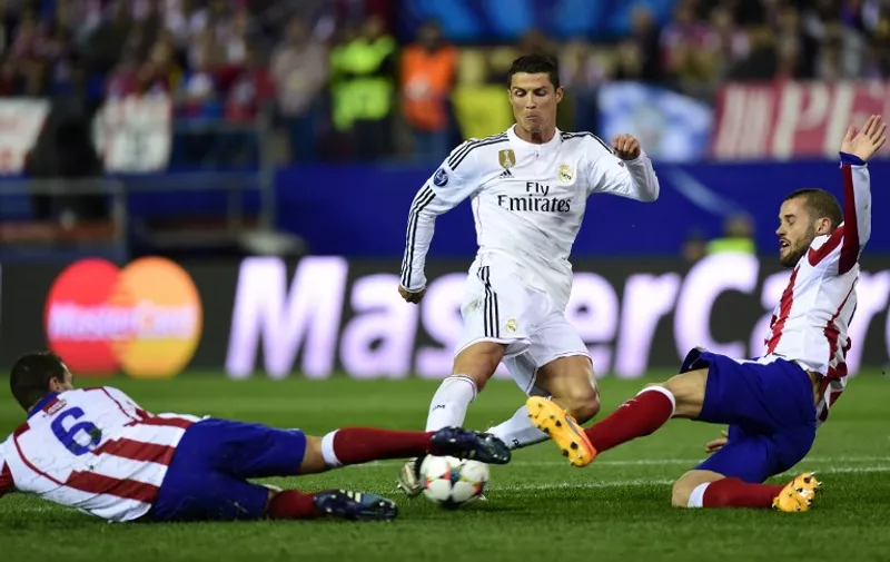 Real Madrid&#8217;s Portuguese forward Cristiano Ronaldo (C) vies with Atletico Madrid&#8217;s midfielder Mario Suarez (R) and Atletico Madrid&#8217;s midfielder Koke during the UEFA Champions League quarter final first leg football match Atletico de Madrid vs Real Madrid CF at the Vicente Calderon stadium in Madrid on April 14, 2015. AFP PHOTO / JAVIER SORIANO