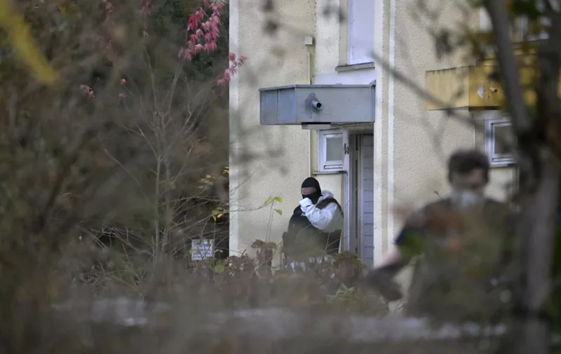 A policeman is seen in front of a residential building during a raid on December 7, 2022 in Berlin that is part of nationwide early morning raids against members of a far-right "terror group" suspected of planning an attack. - During the nationwide raids, police arrested 25 people suspected of belonging to a far-right "terror cell" plotting to overthrow the government and attack parliament. Around 3,000 officers including elite anti-terror units took part in the early morning raids and searched more than 130 properties, in what German media described as one of the country's largest police actions ever against extremists. (Photo by Tobias SCHWARZ / AFP)