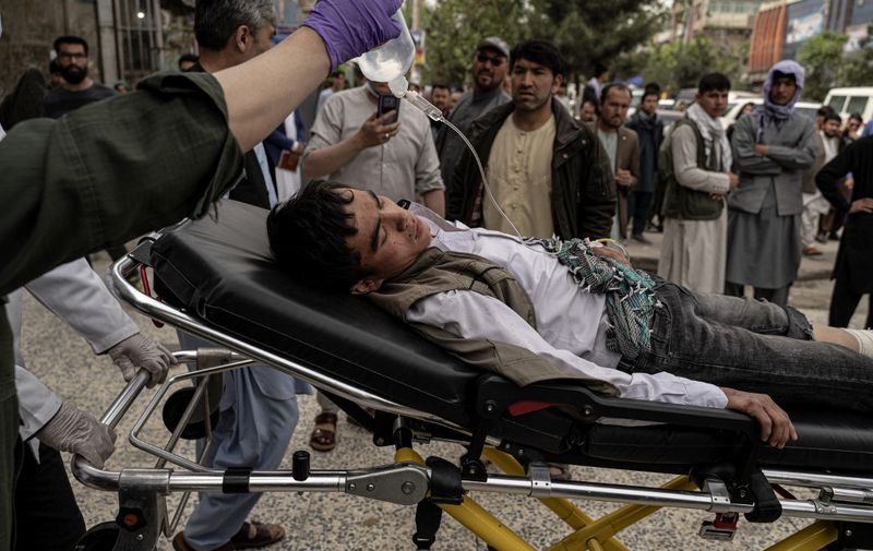 Medical staff move a wounded youth on a stretcher outside a hospital in Kabul on April 19, 2022, after two bomb blasts rocked a boys' school in a Shiite Hazara neighbourhood killing at least 6 people. (Photo by Wakil KOHSAR / AFP)