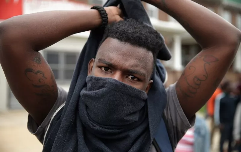 BALTIMORE, MD - APRIL 27: A young man covers his face to protect against pepper spray and tear gas during violent protests following the funeral of Freddie Gray April 27, 2015 in Baltimore, Maryland. Gray, 25, who was arrested for possessing a switch blade knife April 12 outside the Gilmor Homes housing project on Baltimore's west side. According to his attorney, Gray died a week later in the hospital from a severe spinal cord injury he received while in police custody.   Chip Somodevilla/Getty Images/AFP