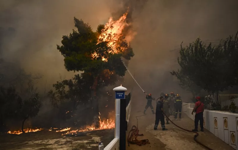 A firefighter sprays water on flames during a wildfire in Chasia in the outskirts of Athens on August 22, 2023. Greece's fire brigade on August 22, 2023 ordered the evacuation of a district on Athens' northwestern flank as firefighters battled a steadily growing wave of wildfires around the country, the second in a month. Tens of thousands of people have been urged to leave the district of Ano Liosia, while at the neighbouring community of Fyli an AFP journalist saw homes on fire. (Photo by Angelos Tzortzinis / AFP)