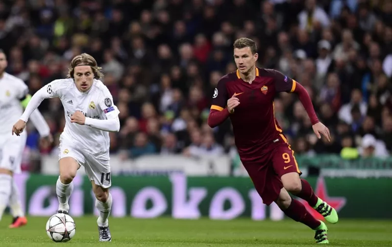 Real Madrid's Croatian midfielder Luka Modric (L) vies with Roma's forward from Bosnia-Herzegovina Edin Dzeko during the UEFA Champions League round of 16 second-leg football match Real Madrid CF vs AS Roma at the Santiago Bernabeu stadium in Madrid on March 8, 2016. / AFP / JAVIER SORIANO