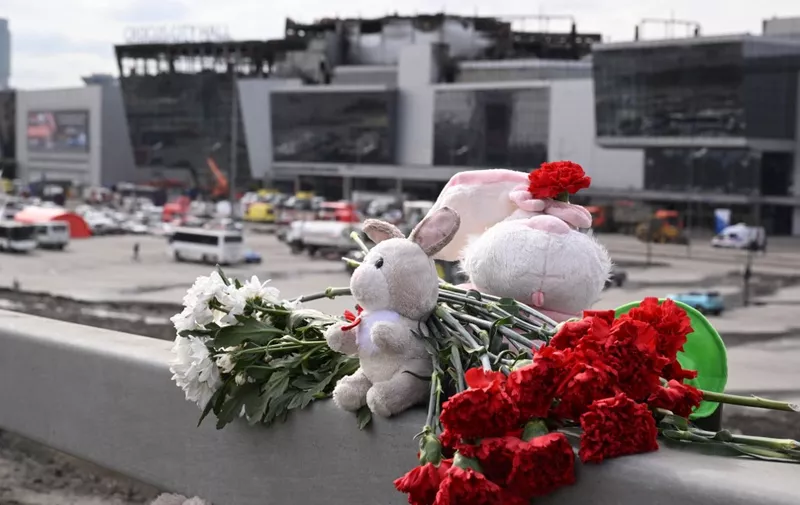 Flowers and toys are seen left at the side of a road near the burnt-out Crocus City Hall concert venue in Krasnogorsk, outside Moscow, on March 26, 2024. At least 139 people were killed when gunmen in camouflage stormed Crocus City Hall, shooting spectators before setting the building on fire in the most fatal attack in Europe to have been claimed by Islamic State jihadists. (Photo by NATALIA KOLESNIKOVA / AFP)