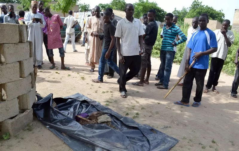 GRAPHIC CONTENT
People look at the dead body of one of the four suicide bombers that blew themselves up in the city of Maiduguri, northeast Nigeria, on October 2, 2015, killing at least 10 people and injuring 39 others. Boko Haram Islamists have increasingly used suicide bombers to target civilians, including in Maiduguri, where on September 20 at least 117 people were killed in a wave of attacks. AFP PHOTO / STRINGER