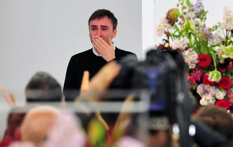 Belgian designer Raf Simons blows a kiss to the audience as he cries at the end of the Jil Sander Fall-winter 2012-2013 collection on February 25, 2012 during the Women's fashion week in Milan. The company announced the day before German fashion designer Jil Sander is set to make a return to the company that bears her name nearly eight years after resigning, with Simons leaving his position of creative director on February 27.  AFP PHOTO / GIUSEPPE CACACE (Photo by GIUSEPPE CACACE / AFP)