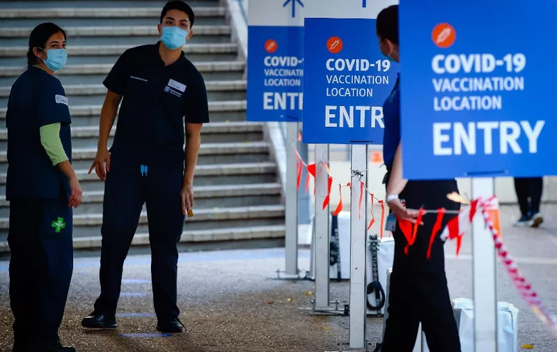 Health workers look on at an entrance to a Covid-19 vaccination hub at the Brisbane Convention and Exhibition Centre in Brisbane on August 17, 2021. (Photo by Patrick HAMILTON / AFP)