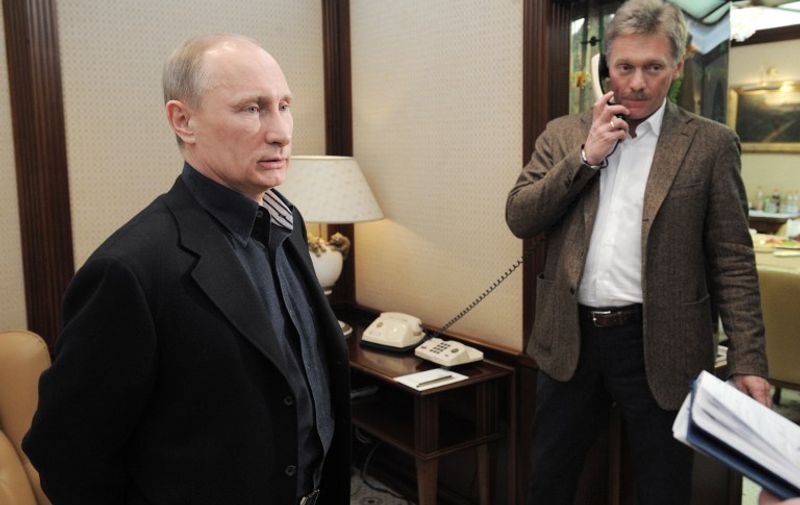 Russia's Prime Minister and presidential candidate Vladimir Putin (L)  looks on as he visits his campaign staff in Moscow, late on March 4, 2012, with Putin's spokesman Dmitry Peskov speaking by phone. Putin reclaimed today the Kremlin in a crushing presidential election victory that he declared was honest but the opposition said was undermined by serial violations. AFP PHOTO/ RIA-NOVOSTI POOL/ ALEXEY DRUZHININ