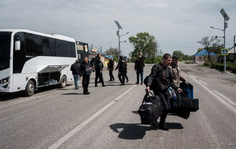 Ukrainian evacuees from Lyman carry thei luggage upon their arrival in Raihorodok, eastern Ukraine, on a bulletproof bus on May 2, 2022, amid the Russian invasion of Ukraine. - Lyman, a former railway hub known as the "red town" for its redbrick industrial buildings, is expected to be one of the next places to fall after Ukrainian forces withdrew. (Photo by Yasuyoshi CHIBA / AFP)