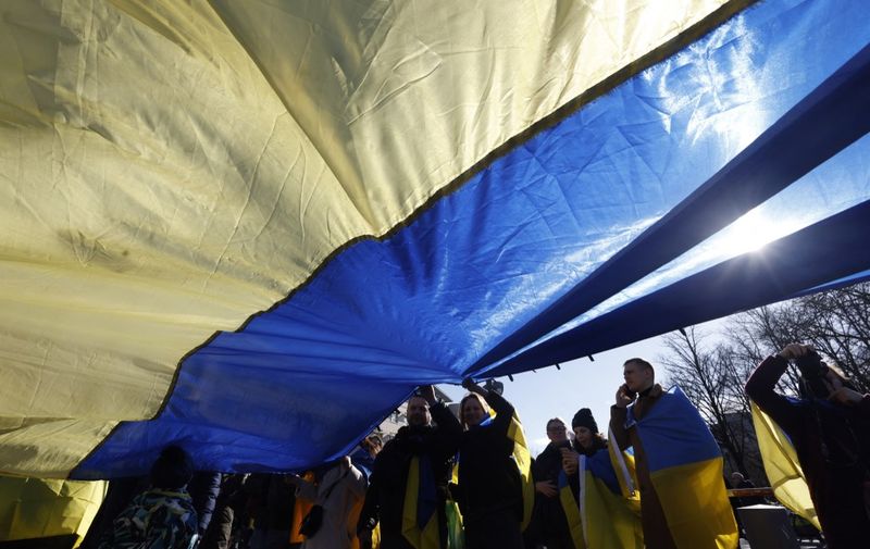 Demonstrators hold a giant flag of Ukraine as they take part in a rally in support of Ukraine, to mark the second year of Russia's military invasion on Ukraine, at the Brandenburg Gate in Berlin on February 24, 2024. (Photo by Odd ANDERSEN / AFP)