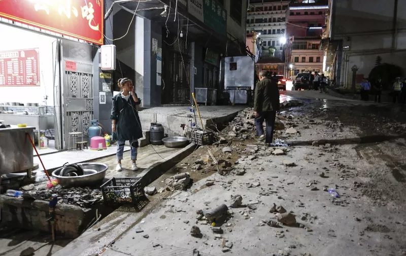 A woman stands outside a restaurant after a 5.0-magnitude earthquake in Qiaojia county, Zhaotong city, in China's southwestern Yunnan province early on May 19, 2020. - Four people were killed and another 23 injured when an earthquake shook southwestern China's Yunnan province, local authorities said on May 19. (Photo by STR / AFP) / China OUT