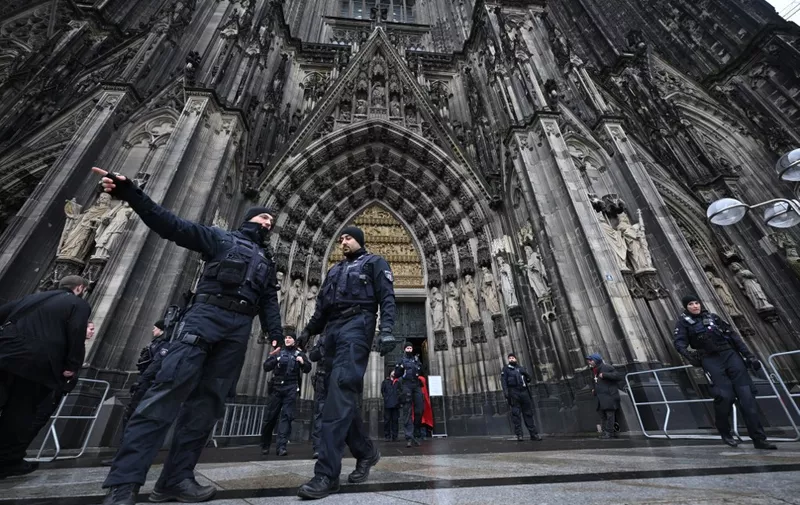 Policemen stand in front of the Cologne Cathedral on December 24, 2023. German police announced on December 23, 2023 evening they were searching the cathedral in the western city of Cologne with sniffer dogs following a "danger warning" for New Year's Eve. The German daily Bild reported that officials in Austria, Germany and Spain have all received indications that an Islamist group was planning several attacks in Europe, possibly on New Year's Eve and Christmas. (Photo by INA FASSBENDER / AFP)