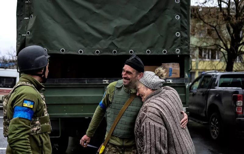An elderly woman embraces an Ukranian soldier in Bucha, northwest of Kyiv, on April 2, 2022, where town's mayor said 280 people had been buried in a mass grave and that the town is littered with corpses. - Ukraine has regained control of "the whole Kyiv region" after invading Russian forces retreated from some key towns near the Ukrainian capital, deputy defence minister said today. (Photo by RONALDO SCHEMIDT / AFP)