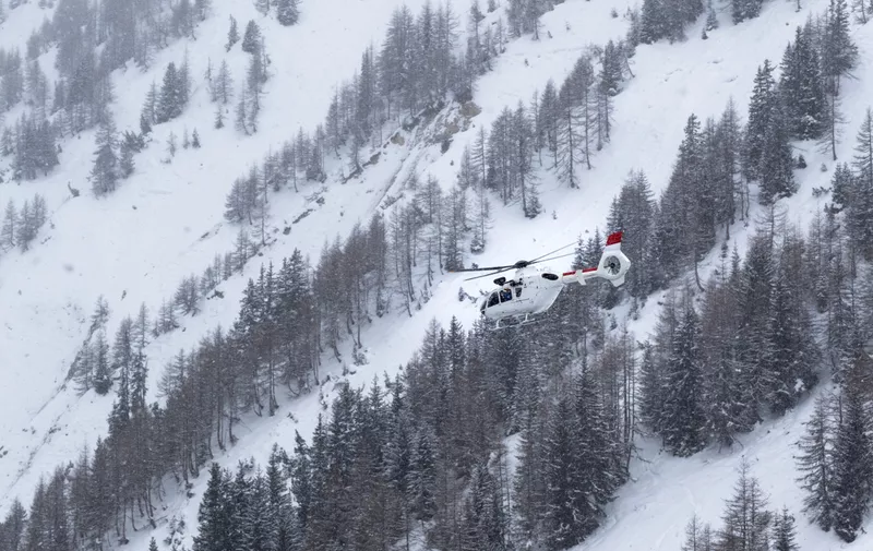 White rescue helicopter flying in heavy snowfall in winter ski resort in French Alps