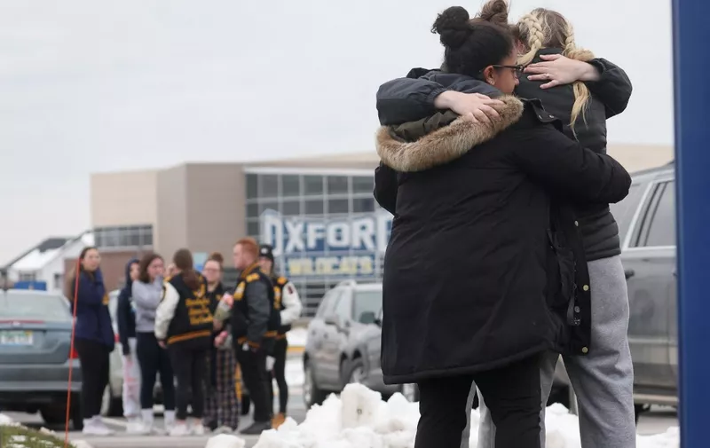 OXFORD, MICHIGAN - DECEMBER 01: People embrace as they visit a makeshift memorial outside of Oxford High School on December 01, 2021 in Oxford, Michigan. On Tuesday, three students were killed and eight injured when a gunman opened fire at the school. A fourth student died on Wednesday. The suspect, identified as 15-year-old Ethan Crumbley, has been charged as an adult with terrorism and first-degree murder.   Scott Olson/Getty Images/AFP (Photo by SCOTT OLSON / GETTY IMAGES NORTH AMERICA / Getty Images via AFP)