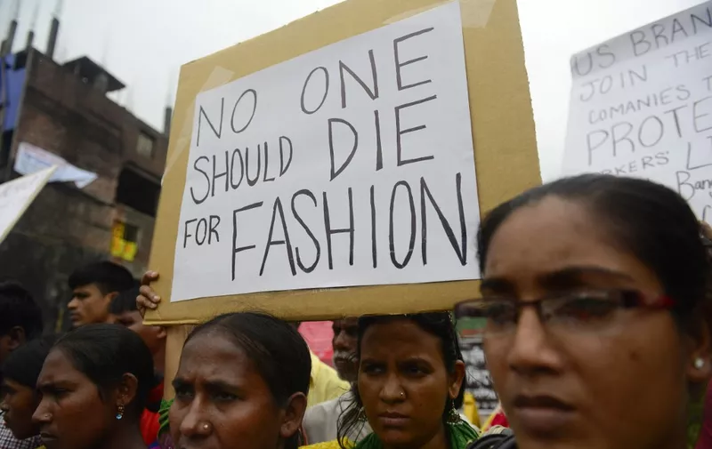 Relatives of Bangladeshi workers who lost their lives in the nine-storey Rana Plaza garment factory building collapse, gather with banners and placards in Savar, on the outskirts of Dhaka on June 29, 2013, at the site of Bangladesh's worst industrial disaster. Activists are set to protest across North America and Europe as they attempt to force the clothing retail giants Gap and Walmart into signing an 'Accord on Fire and Building Safety in Bangladesh', which holds corporations legally responsible for the safety of garment workers in the South Asian nation.   Bangladeshi officials have said Dhaka has enacted a series of reforms since the April 24, collapse of a factory complex in which 1,129 people were killed -- the latest in a series of disasters to blight the industry.    AFP PHOTO/Munir uz ZAMAN (Photo by Munir UZ ZAMAN / AFP)