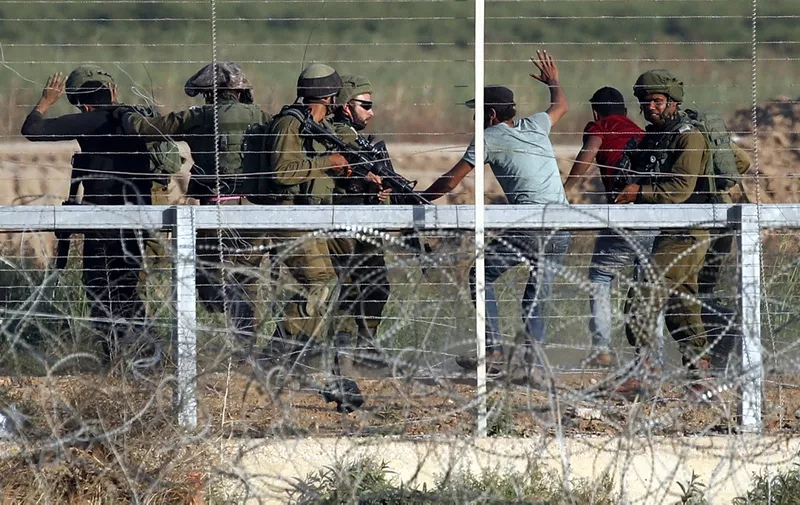 Israeli soldiers arrest three Palestinians who tried to approach the Israeli border fence during clashes east of Gaza City on May 15, 2018, amidst protests marking 70th anniversary of Nakba -- also known as Day of the Catastrophe in 1948 -- and against the US' relocation of its embassy from Tel Aviv to Jerusalem. (Photo by THOMAS COEX / AFP)
