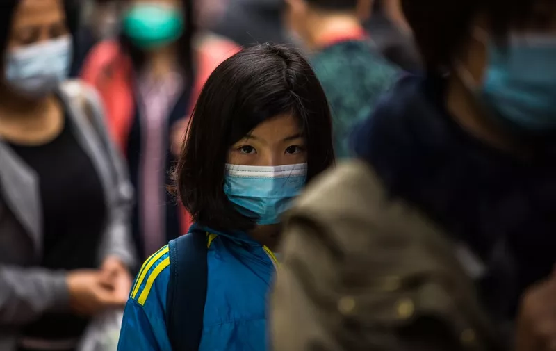 People wearing protective face masks walk along a street in Hong Kong on February 9, 2020, as a preventative measure after a coronavirus outbreak which began in the Chinese city of Wuhan. - The previously unknown virus has caused alarm because of its similarity to SARS (Severe Acute Respiratory Syndrome), which killed hundreds across mainland China and Hong Kong in 2002-2003. (Photo by DALE DE LA REY / AFP)