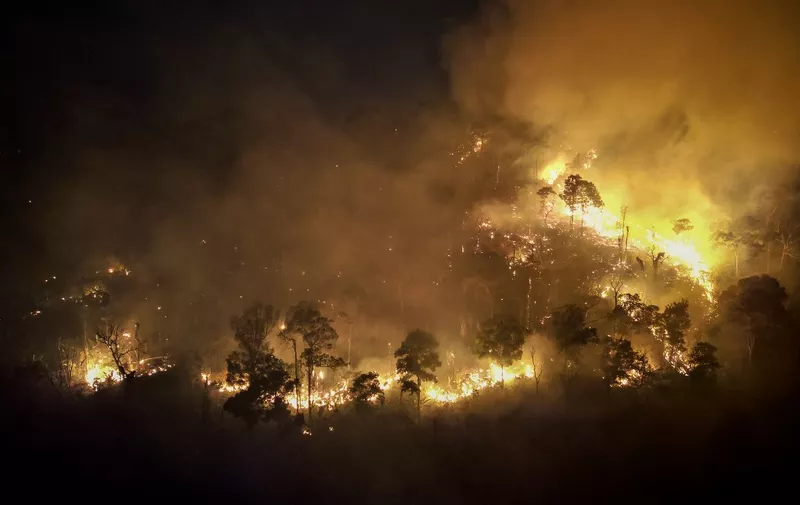 A forest fire burns on a mountain-side in Nakhon Nayok province, northeast of Bangkok on March 31, 2023. - Hundreds of Thai firefighters and soldiers battled a forest blaze less than 100 kilometres from Bangkok as the kingdom grapples with air pollution. (Photo by Jack TAYLOR / AFP)