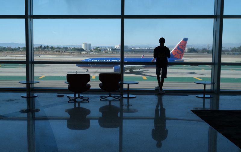 A person watches planes take off from the Tom Bradley International terminal at Los Angeles International Airport (LAX) in Los Angeles, California, on August 10, 2022. (Photo by Chris Delmas / AFP)