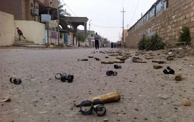 A picture taken with a mobile phone on January 3, 2014 shows people in a street with empty bullets on the groud following fighting between Islamist jihadists and Iraqi special forces in the Iraqi city of Ramadi, west of Baghdad. Fighting began in the Ramadi area on December 30, 2013, when security forces removed the main anti-government protest camp set up after demonstrations broke out in late 2012 against what Sunni Arabs say is the marginalisation and targeting of their community.  AFP PHOTO/AZHAR SHALLAL