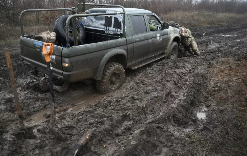 Ukrainian servicemen push a car stuck in mud on a field road on the frontline in Donetsk region, on December 17, 2022, amid the Russian invasion of Ukraine. (Photo by Genya SAVILOV / AFP)