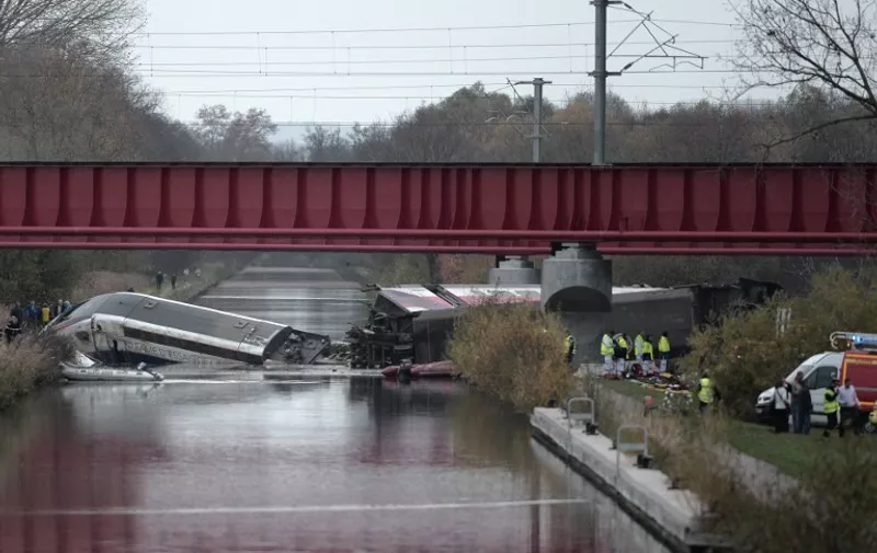 Rescuers work at the scene where a high-speed TGV train coach and engine carriage lie in a canal in Eckwersheim near Strasbourg, northeastern France, after derailing on November 14, 2015 during tests conducted by technicians, Frenh railway operator SNCF said. At least five were killed in French high-speed train test on November 14, due to excessive speed, sources said. AFP PHOTO / FREDERICK FLORIN