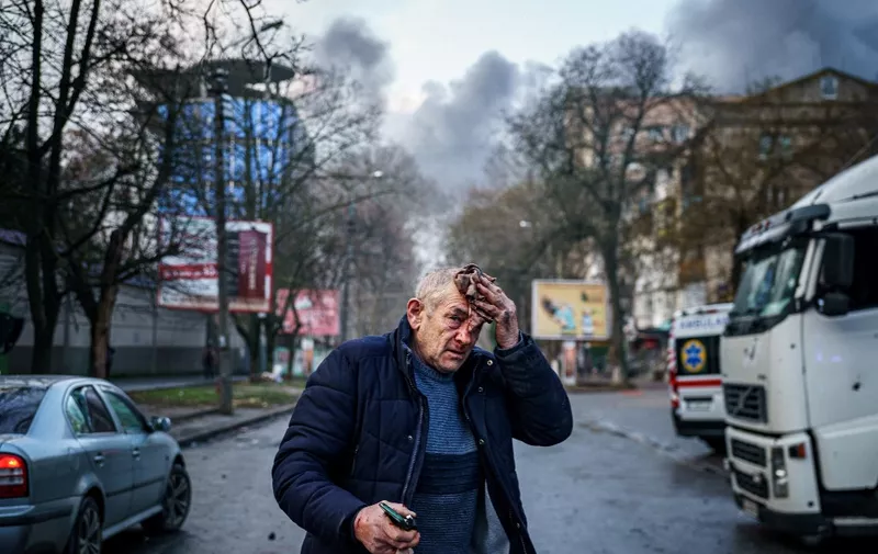 An injured man stands on a street after Russian shelling to Ukrainian city of Kherson on December 24, 2022, where five were killed and 20 injured. - Ukrainian President Volodymyr Zelensky on December 24, 2022 blasted Russian "terror" after shelling left at least five dead and 20 injured in Kherson city, which Kyiv's forces recaptured in November. (Photo by Dimitar DILKOFF / AFP)