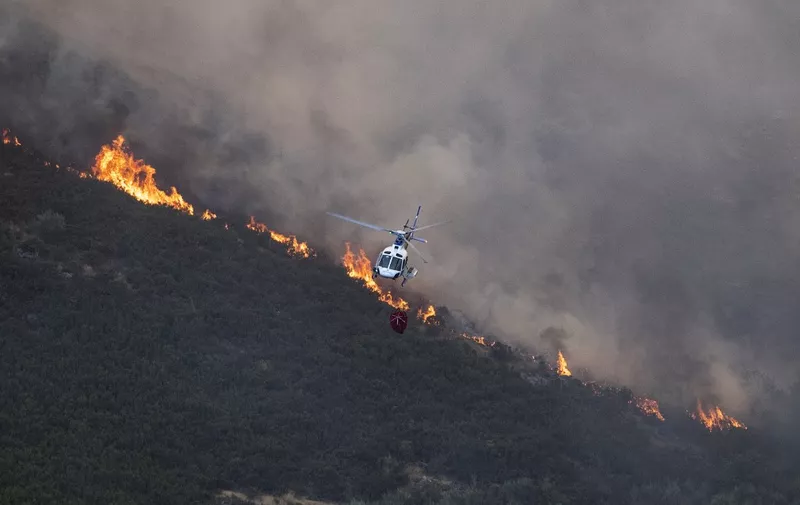 A firefighter helicopter flies over a wildfire in the Baixa Limia - Serra do Xures Natural Park near the village of Lobeira, Ourense province, northwestern Spain, on August 25, 2022. (Photo by MIGUEL RIOPA / AFP)