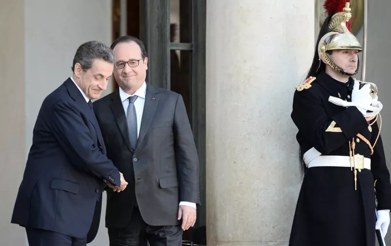 French President Francois Hollande (R) and right-wing Les Republicains (LR) party's president and former French president Nicolas Sarkozy, shake hands after a meeting at the Elysee Palace, in Paris on November 15, 2015. AFP PHOTO / STEPHANE DE SAKUTIN