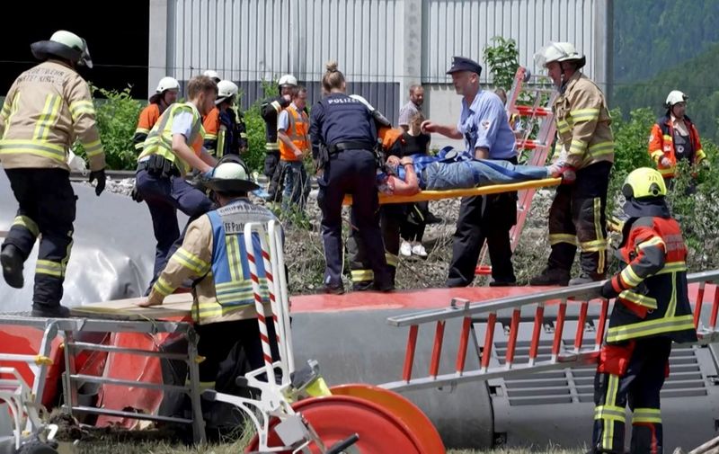 This video grab shows policemen and firemen rescuing a person from a derailed train on June 3, 2022 in Burgrain near Garmisch-Partenkirchen, southern Germany. - At least three people were killed and several others injured as a train derailed near a Bavarian Alpine resort in southern Germany, police said. (Photo by NETWORK PICTURES / AFP)