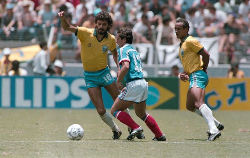 French Alain Giresse (C) vies with Brazilian players Socrates (L) and Elzo (R), on June 21, 1986 in Guadalaraja, during the World Cup quarterfinal soccer match between France and Brazil. / AFP PHOTO / STRINGER