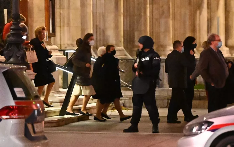 Opera guests leave the state opera under the supervision of armed policemen, in the center of Vienna on November 2, 2020, following a shooting. - Two people, including one attacker, have been killed in a shooting in central Vienna, police said late November 2, 2020. Vienna police said in a Twitter post there had been "six different shooting locations" with "one deceased person" and "several injured", as well as "one suspect shot and killed by police officers". (Photo by Joe Klamar / AFP)