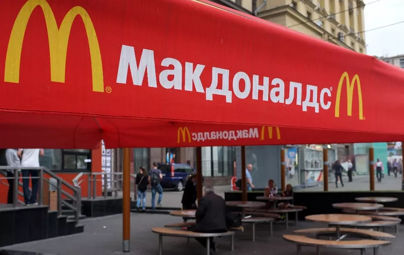 People sit on the terrace of a closed McDonald's restaurant, the first to be opened in the Soviet Union in 1990, in Moscow on August 21, 2014. Russian authorities shuttered four Moscow McDonald's due to alleged sanitary violations on August 20, 2014, including a restaurant that once symbolised reviving Soviet-US ties, as tensions sizzled over Ukraine.  The announcement comes in the wake of Russian bans on US and EU food imports in response to Western sanctions over Moscow's perceived backing for rebels in eastern Ukraine.
AFP PHOTO / ALEXANDER NEMENOV (Photo by ALEXANDER NEMENOV / AFP)