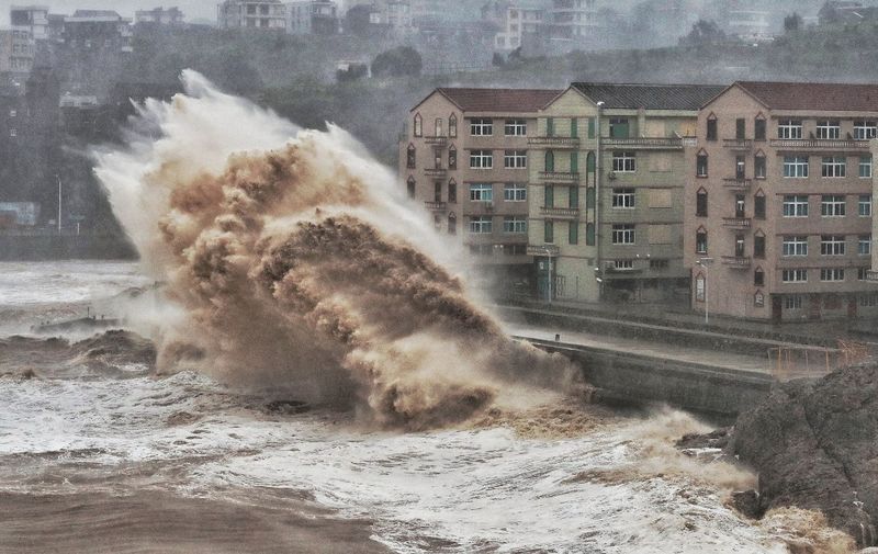 Waves hit a sea wall in front of buildings in Taizhou, China's eastern Zhejiang province on August 9, 2019. - China issued a red alert for incoming Super Typhoon Lekima which is expected to batter eastern Zhejiang province early on August 10 with high winds and torrential rainfall. (Photo by - / AFP) / China OUT