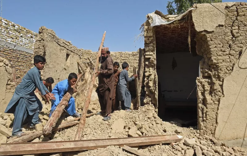Residents remove debris of their damaged mud houses following an earthquake in the remote mountainous district of Harnai on October 7, 2021, as at least 20 people were killed and dozens injured when a shallow earthquake hit southwestern Pakistan in the early hours of October 7. (Photo by Banaras KHAN / AFP)