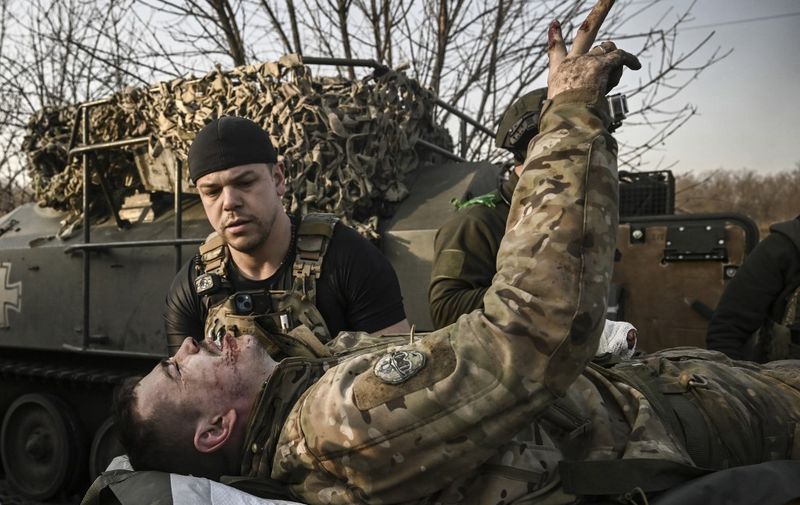 A wounded Ukrainian seviceman flashes the V-sign as he is being carried away from the front line near Bakhmut, on March 23, 2023. (Photo by Aris Messinis / AFP)