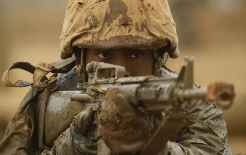 A female United States Marine Corps (USMC) recruit from Lima Company, the first gender integrated training class in San Diego, aims their rifle while covered in mud following an obstacle course during The Crucible, the final part of phase three of recruit training before officially becoming US Marines on April 21, 2021 at Camp Pendleton in San Diego County, California. - Lima Company is the first gender integrated company with a female platoon training alongside male platoons at the west coast Marine Corps Recruit Depot, San Diego (MCRDSD). The Crucible is the final 54-hour test for the recruits, where upon completion the recruits will receive their eagle, globe, and anchor pin to officially become US Marines. Recruits had to spend two weeks in quarantine before beginning training due to the Covid-19 pandemic. Congress ordered the Marine Corps to fully integrate women into its west coast training battalions by 2028 under the National Defense Authorization Act. Women make up about 9 percent of the Marine Corps. (Photo by Patrick T. FALLON / AFP)