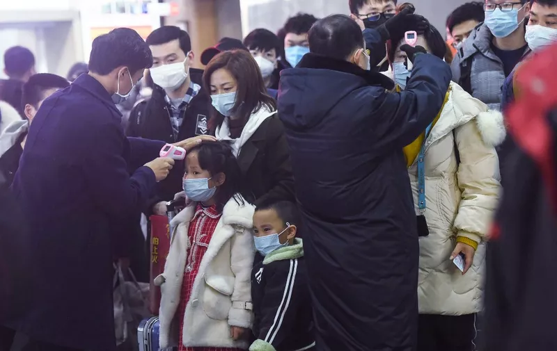 Staff members (in black) check the body temperature of passengers after a train from Wuhan arrived at Hangzhou Railway Station in Hangzhou, China's eastern Zhejiang province. - China banned trains and planes from leaving a major city at the centre of a virus outbreak on January 23, seeking to seal off its 11 million people to contain the contagious disease that has claimed 17 lives, infected hundreds and spread to other countries. (Photo by STR / AFP) / China OUT