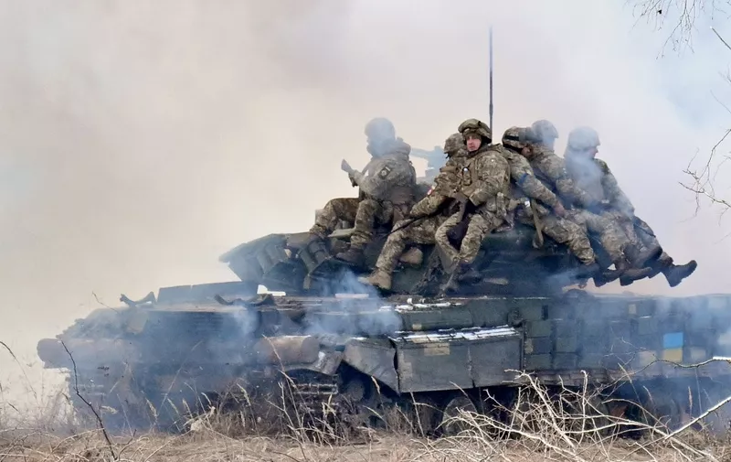 Ukrainian soldiers sit atop main battle tanks deploying smokescreens as they take part in military drills as they work out a possible attack in Chernobyl zone in few kilometers from the border with Belarus on February 20, 2023. (Photo by Sergei SUPINSKY / AFP)