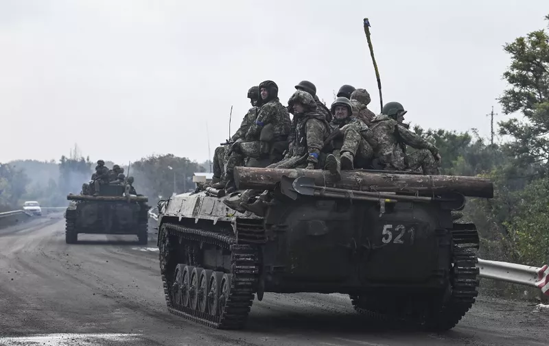 Ukrainian soldiers sit on infantry fighting vehicles as they drive near Izyum, eastern Ukraine on September 16, 2022, amid the Russian invasion of Ukraine. (Photo by Juan BARRETO / AFP)