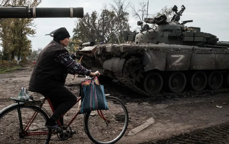 A local resident rides past an abandoned Russian tank marked Z in Kyrylivka, in the recently retaken area near Kharkiv, on September 30, 2022. (Photo by Yasuyoshi CHIBA / AFP)