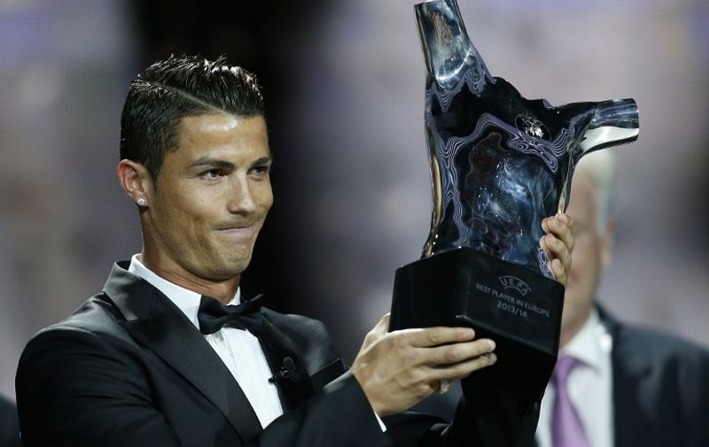 Real Madrid's Portuguese forward Cristiano Ronaldo celebrates holding his UEFA European Player of the Year trophy, on August 28, 2014 in Monaco, after the draw for the 2014/2015 European Champions League group stages. AFP PHOTO / VALERY HACHE