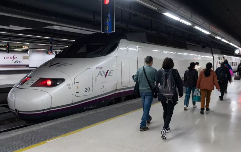Passengers walk past an AVE high-speed train at Barcelona-Sants railway station prior to departing to Lyon on a test trip along a new international rail line between Spain and France, in Barcelona on February 13, 2023. (Photo by Josep LAGO / AFP)