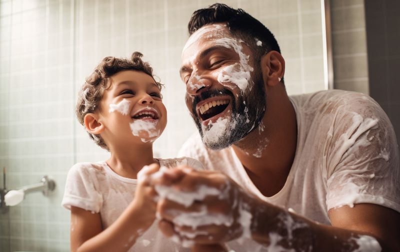 Father and son in the bathroom having fun and shaving, foam on their faces, generative ai