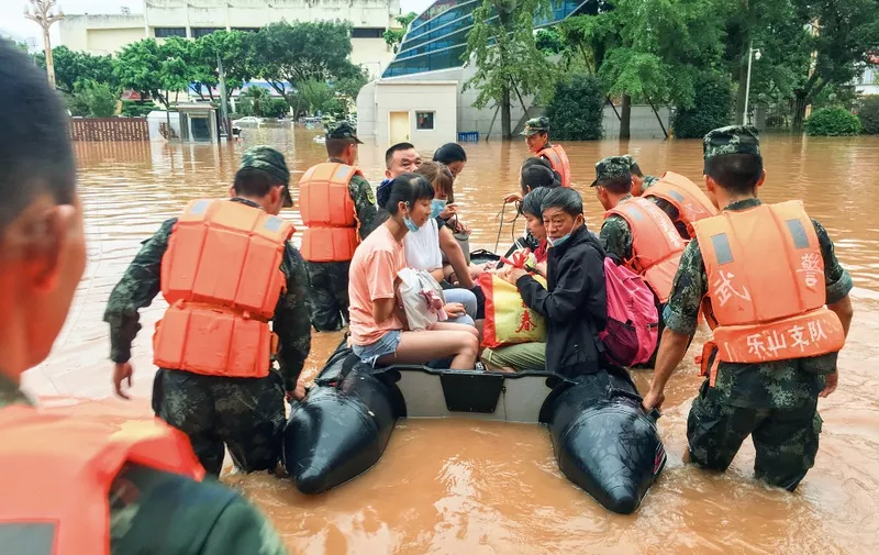 This photo taken on August 18, 2020 shows rescuers evacuating residents at a flooded area following heavy rains in Leshan in China's southwestern Sichuan province. - Floods in mountainous southwest China have washed away roads and forced tens of thousands from their homes, with authorities warning on August 19 the giant Three Gorges Dam was facing the largest flood peak in its history. (Photo by STR / AFP) / China OUT