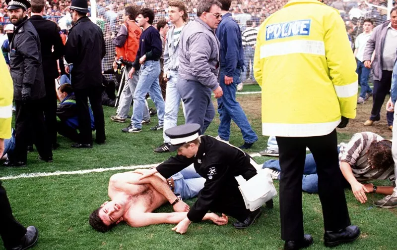 Policemen rescue soccer fans at Hillsborough stadium 15 April 1989 when 96 fans were crushed to death and hundreds injured after support railings collapsed during a match between Liverpool and Nottingham forest. / AFP PHOTO