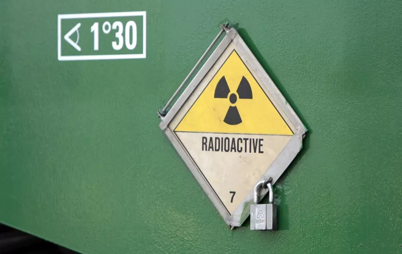 A picture taken on November 22, 2011 shows a radioactivity warning symbol on a "CASTOR" (Cask for Storage and Transportation of Radioactive Material) container carrying highly radioactive nuclear waste which is part of a convoy waiting at the Areva's train station in Valognes, northwestern France, a day before leaving for Gorleben in Germany. Despite massive police forces deployment, anti-nuclear protests are expected in France and Germany against the transport of the eleven so-called "CASTORS" containing nuclear waste. AFP PHOTO / KENZO TRIBOUILLARD (Photo by Kenzo TRIBOUILLARD / AFP)