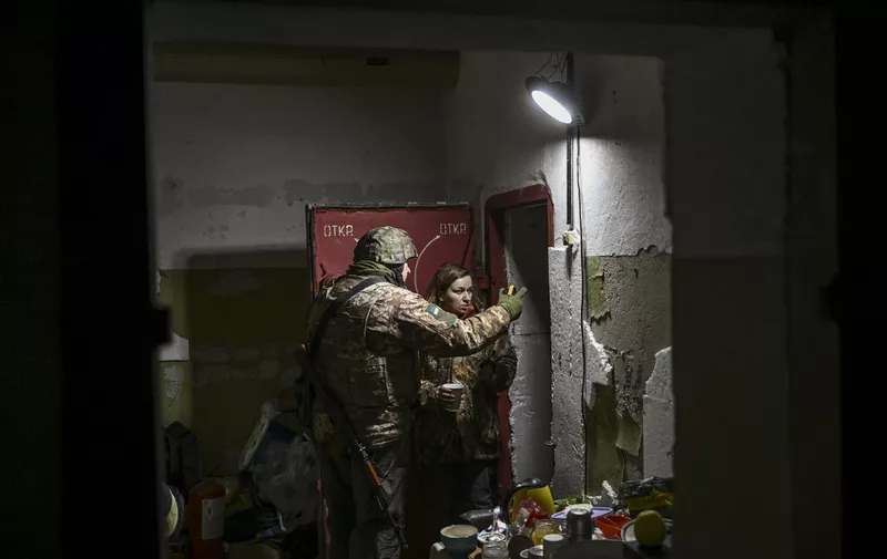 A Ukrainian serviceman talks with a resident in a basement for shelter in the city of Irpin, north of Kyiv, on March 10, 2022. - Russian forces on March 10, 2022 rolled their armoured vehicles up to the northeastern edge of Kyiv, edging closer in their attempts to encircle the Ukrainian capital. Kyiv's northwest suburbs such as Irpin and Bucha have been enduring shellfire and bombardments for more than a week, prompting a mass evacuation effort. (Photo by Aris Messinis / AFP)